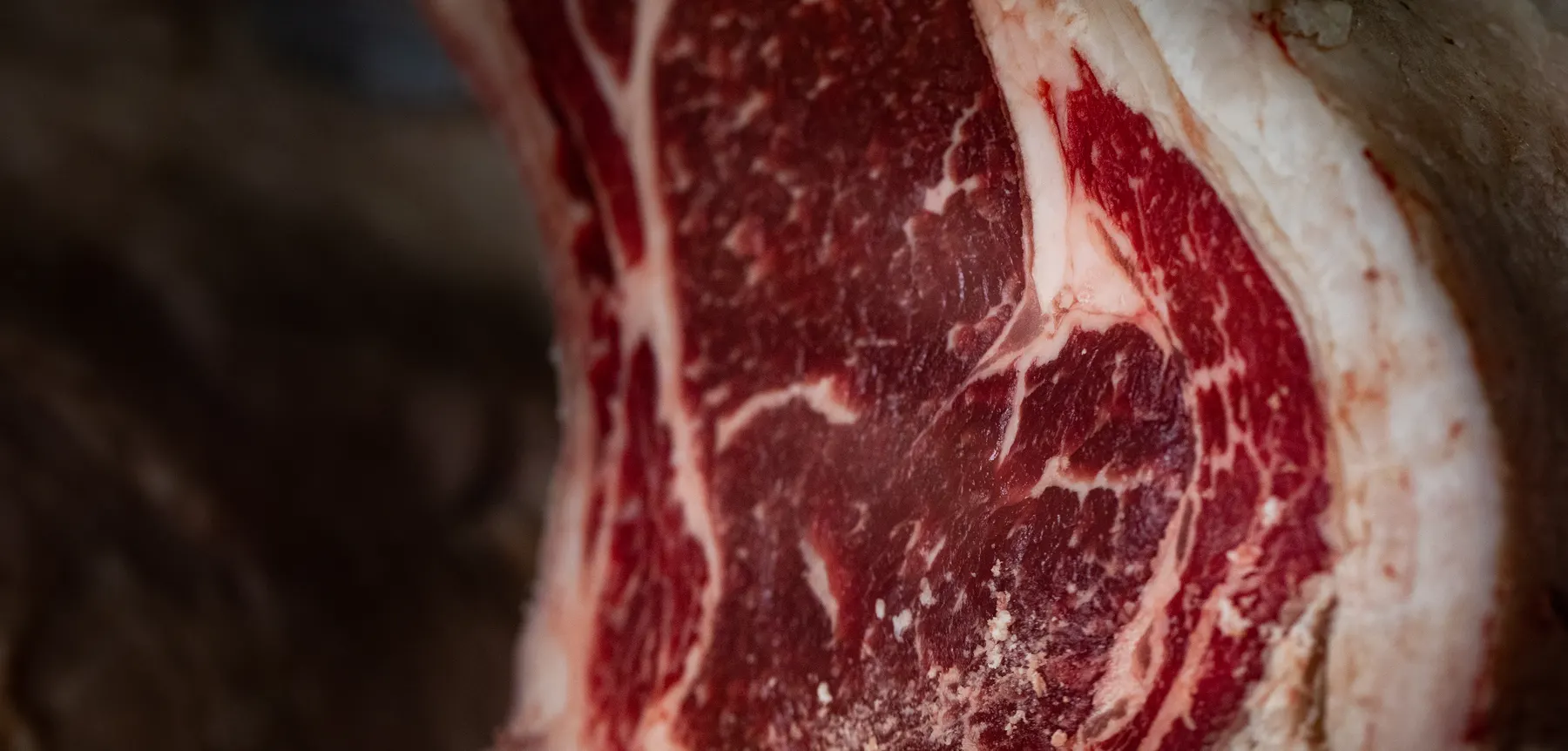 Prim-plan pe secțiunea unui antricot de vită maturat: marmorare fină și coaja uscată la margine